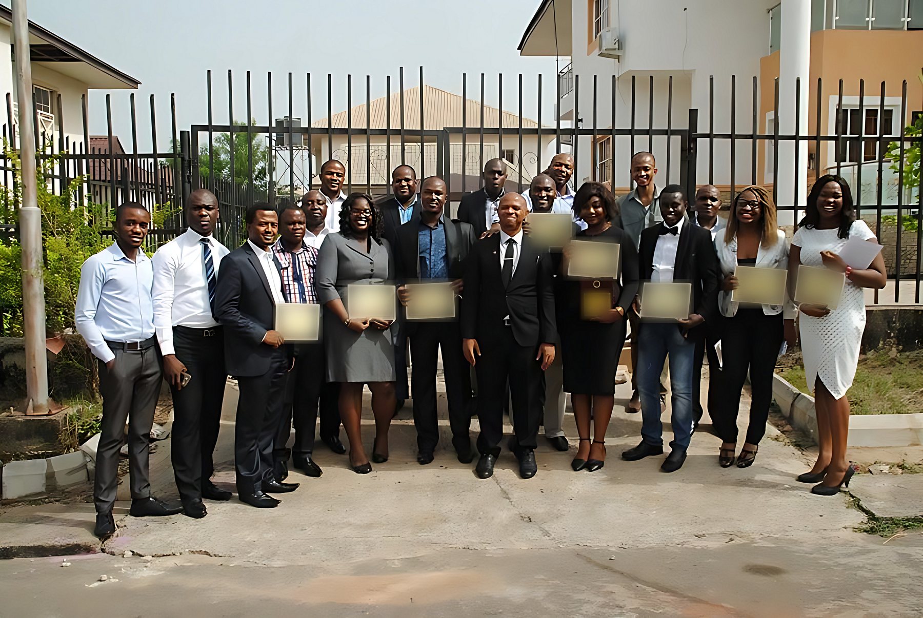 A cohort of professionals holding course completion certificates outdoors